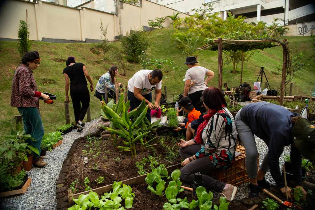 Grupo de moradores plantando em horta em condomínio com canteiros integrados ao paisagismo