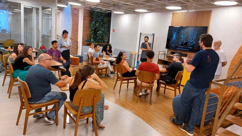Síndicos e moradores participam de reunião em espaço moderno com recursos audiovisuais, representando o uso da tecnologia na gestão inteligente de condomínios para ilustrar artigo de blog