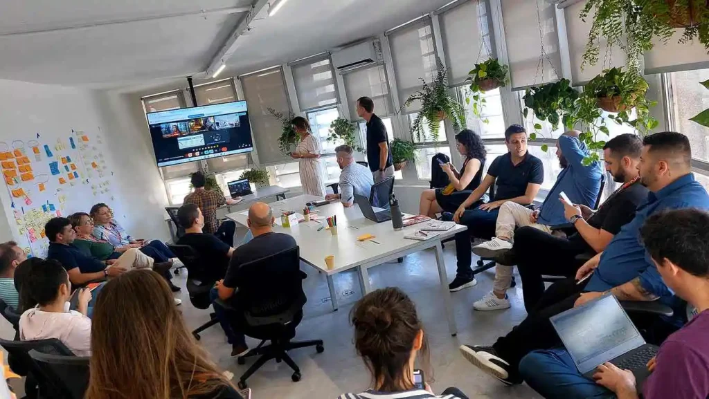 Imagem de uma reunião com síndicos e moradores assistindo a apresentação em ambiente moderno, ilustrando o uso de plataforma digital para síndico na rotina condominial
