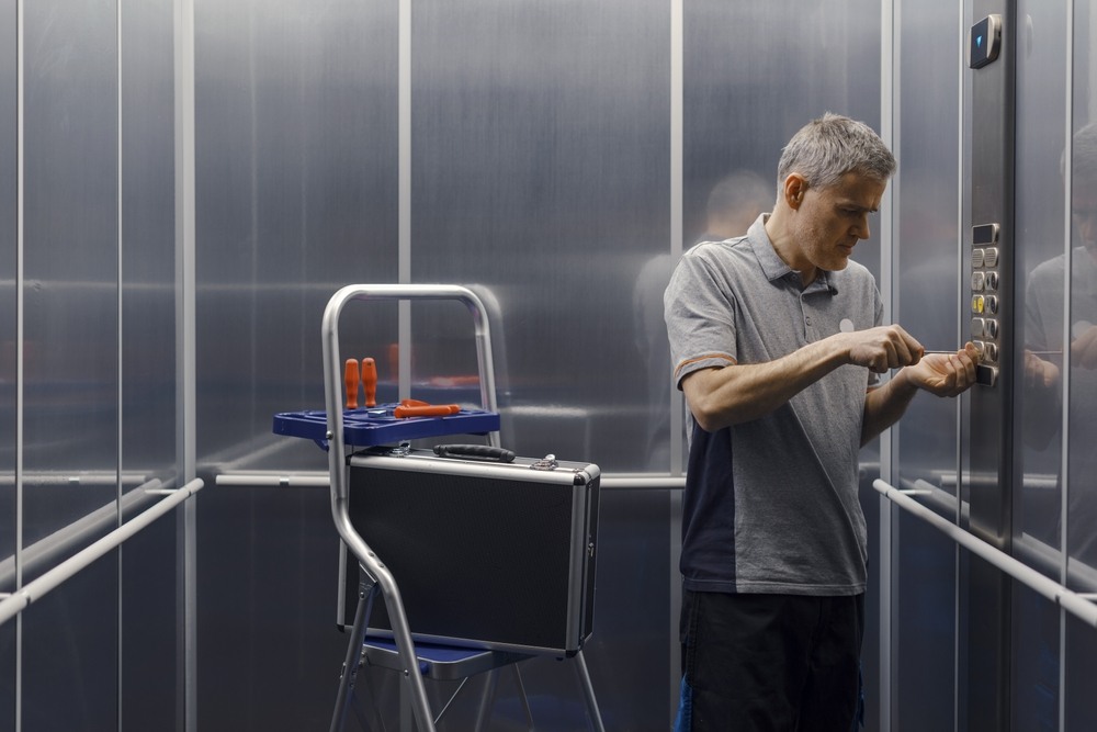 Profissional realiza inspeção técnica e ajustes no elevador de condomínio ilustrando artigo sobre manutenção condominial.