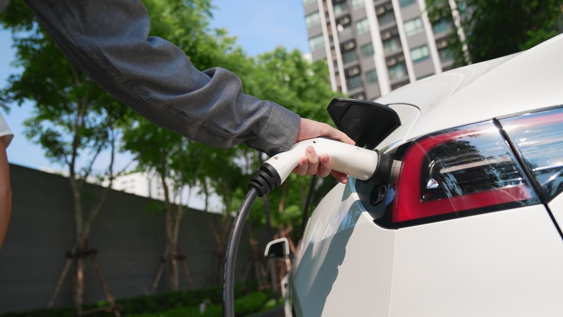 Detalhe de carregamento de carro elétrico em área residencial, evidenciando boas práticas para veículos elétricos em condomínios