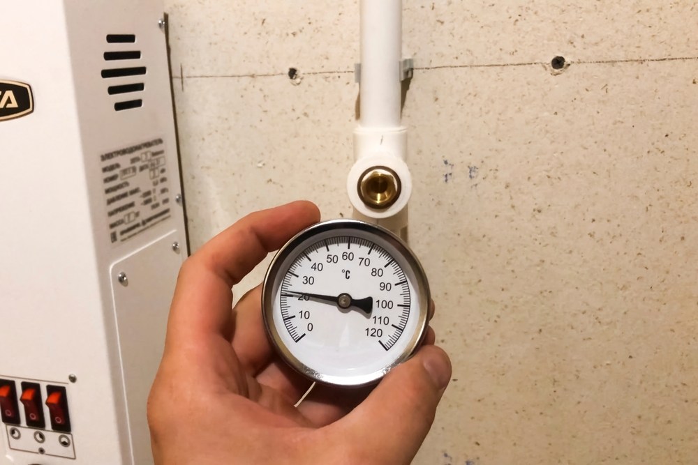 Mão segurando um medidor analógico acoplado a uma tubulação hidráulica, com mostrador circular indicando valores numéricos, ilustrando artigo sobre reajuste da tarifa de água da SABESP em 2026