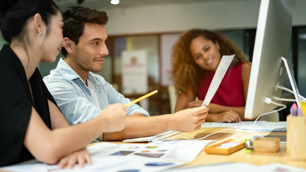 imagem de três pessoas em sala de reuniões, na frente de uma tela de computador, ilustrando artigo sobre gestão de crise em condomínios