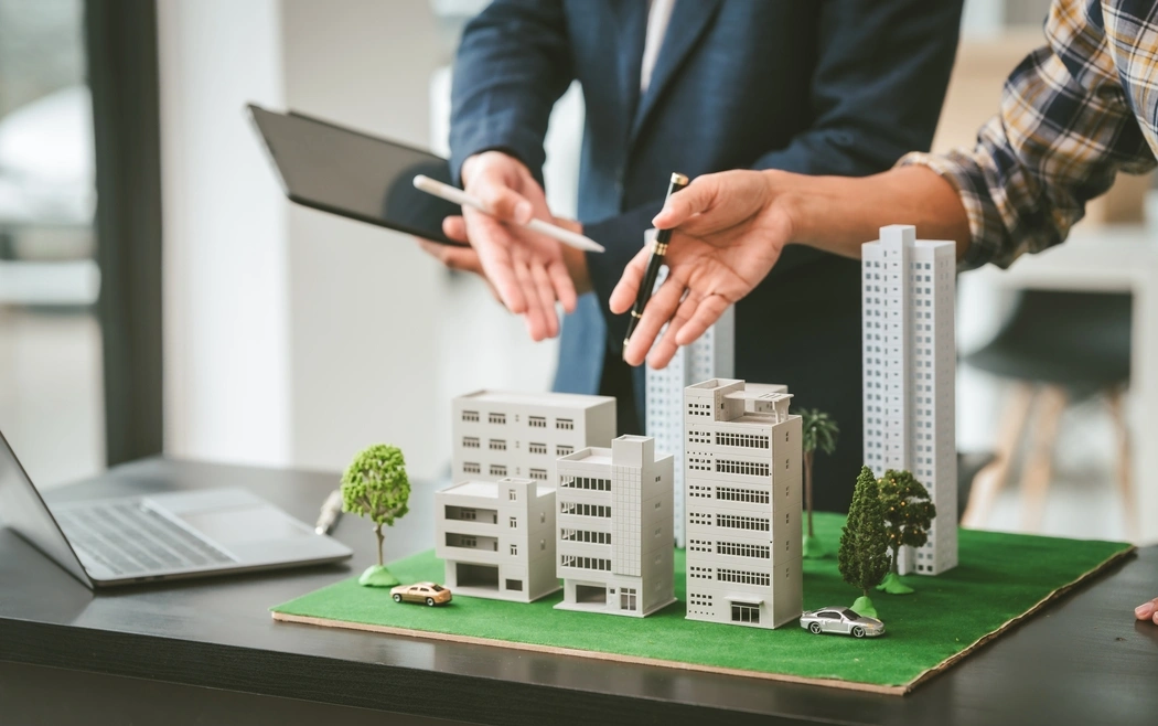 Gestão de crise em condomínios: profissionais analisando maquete de prédios para planejar decisões estratégicas na administração condominial.